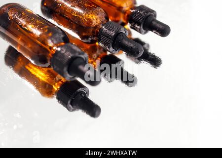 Brown serum or oil glass mock up three bottles with pipette on white background. Group of bottles with drops on them and their r Stock Photo