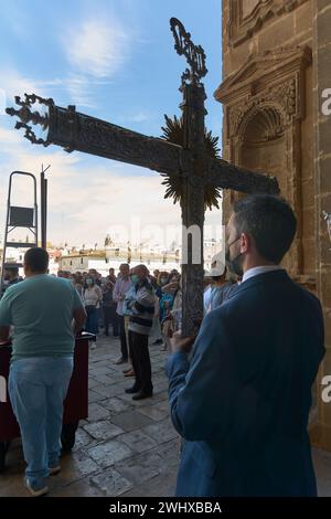 Jerez de la Frontera, Spain - February 11, 2024: Religious procession in holy week, showing an ornate cross, worshipers and the historic architecture Stock Photo