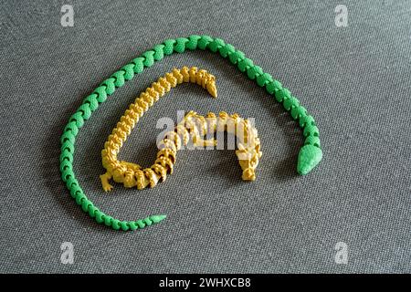 Two complex detailed flexible 3D printed dragon snake models, 3d print manufactured bending multi element dragon model projects printed in one piece, Stock Photo