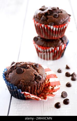 Double chocolate muffins stacked and paper liner opened on rustic wooden boards in vertical format Stock Photo