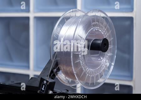 A roll of white transparent high quality 3D printing filament mounted on a modern 3D printer device, closeup. Consumer grade thermoplastic materials u Stock Photo