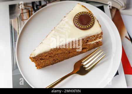 Slice of carrot cake on a white plate with a golden fork Stock Photo