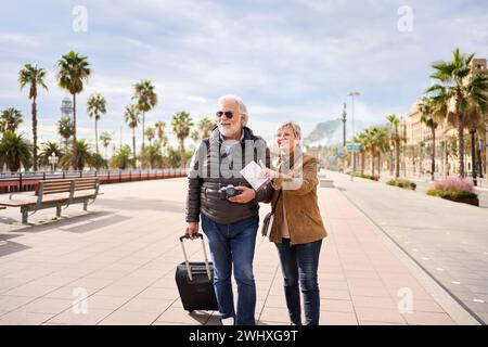 Older Caucasian tourist couple smiling looking and pointing interest places. Senior tourism people. Stock Photo