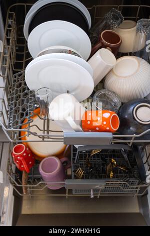 A lot of dirty dishes in the dishwasher. Helping the hostess, economy and ecology. Cleaning in the kitchen Stock Photo