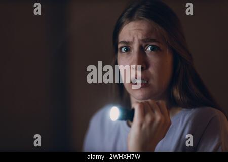 Woman scared holding hand flashlight in darkness and afraid of violence criminal robbery. Stock Photo