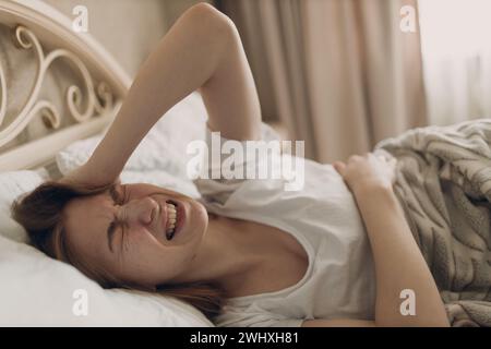 Young woman suffering with headache flu ill sick disease cold at home indoor lying on bed. Stock Photo