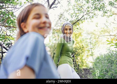 Two happy female teenagers of different nationalities and faiths in the park after training. Stock Photo