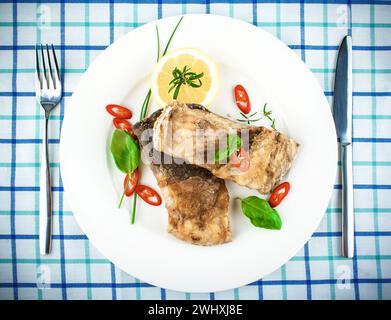 Fried fish on white plate and fork, knife Stock Photo