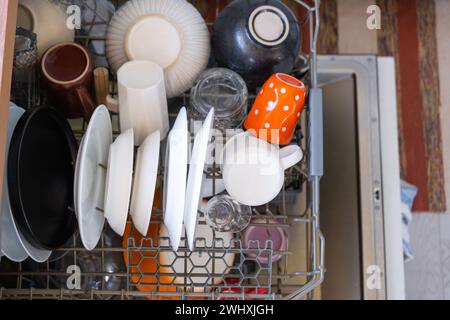 A lot of dirty dishes in the dishwasher. Helping the hostess, economy and ecology. Cleaning in the kitchen Stock Photo