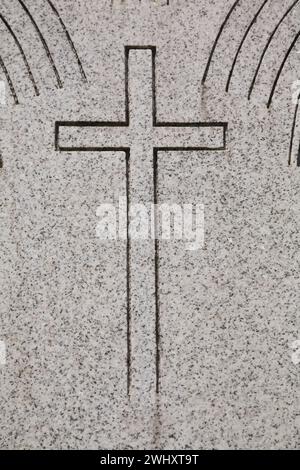 Cross engraved in grey granite headstone in cemetery. Stock Photo