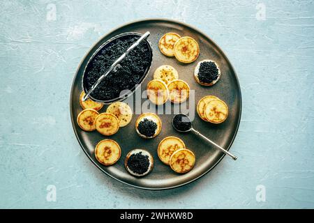 Blinis with black caviar and cream cheese, overhead flat lay shot Stock Photo