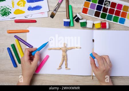 Set of watercolor paints, brushes and paper with different strokes and colors. Female hands holding a felt-tip pen Stock Photo