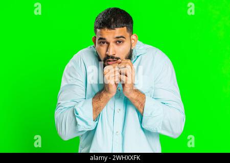 Stressed depressed Indian man terrified about danger problems, suffering phobia, anxiety disorder, expresses fear, waving no, insecure, stress, panic. Scared fearful guy on green chroma key background Stock Photo