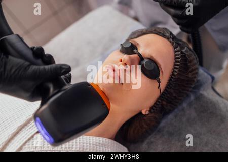Young brunette woman receiving photo epilation while visiting beauty center on salon Stock Photo