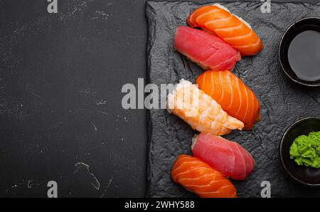 Traditional Japanese sushi with soy sauce, wasabi, chopsticks top view on dark black rustic slate. Sushi with salmon, tuna, shri Stock Photo