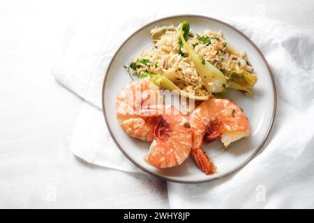 Prawns or shrimps with spicy rice and pak choi on a white plate and a light background, homemade Asian seafood meal, top view fr Stock Photo