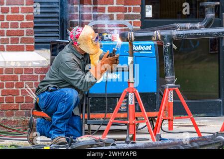 NEW ORLEANS, LA, USA - DECEMBER 27, 2023: Sparks fly as welder in full protective gear welds pipes for a construction project Stock Photo