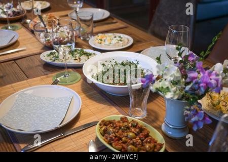 Set rustic wooden table with various homemade salads and appetizers for a casual convivial evening dinner with friends or family Stock Photo