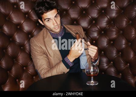 Portrait, cigar and businessman smoking at pub, fashion and serious person in a suit with alcohol at vintage bar. Face, mafia and drinking whiskey Stock Photo