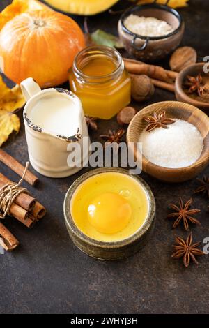 Homemade fall baking background with ingredients pumpkins, sugar, flour, nuts, eggs and spices on a dark stone table. Stock Photo