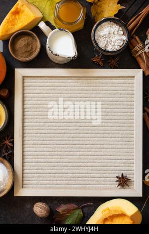 Homemade fall baking background with ingredients pumpkins, sugar, flour, nuts, eggs and spices on a dark stone table. Stock Photo