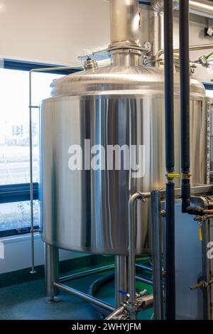 Stainless steel brewing equipment: large reservoir or tank and pipes in a small modern beer factory. Stock Photo