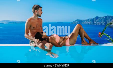 Couple at luxury vacation Greece, Oia Santorini Infinity pool looking out over ocean of Santorini Stock Photo