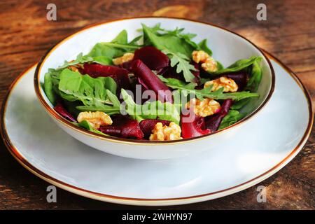Healthy Beet Salad with fresh sweet baby spinach, arugula, nuts on wooden background Stock Photo