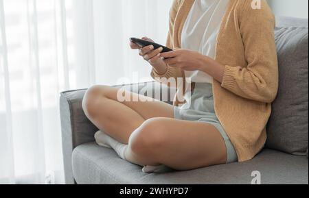 Woman Watching smart TV and using remote controller Hand holding popcorn at home Stock Photo