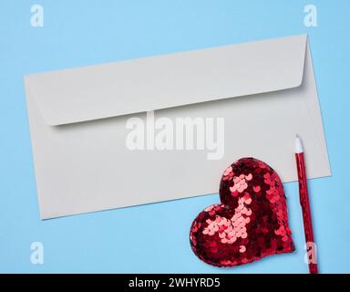 White envelope, red heart on a blue background, top view Stock Photo