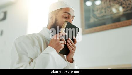 Islam, kiss and man in mosque with Quran, mindfulness and gratitude in faith reading. Worship, religion and love, Muslim Imam in holy temple for Stock Photo