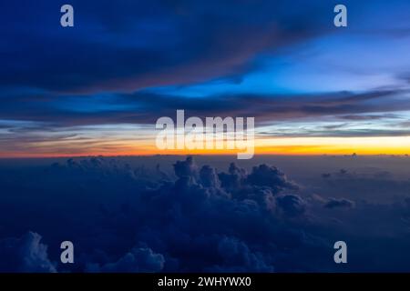 Dark heavy thunderstorm cumulus clouds in the morning at dawn, cloudscape view from an airplane. Stock Photo