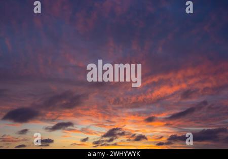 Beautiful fiery orange sunset sky with dark textures clouds. Stock Photo