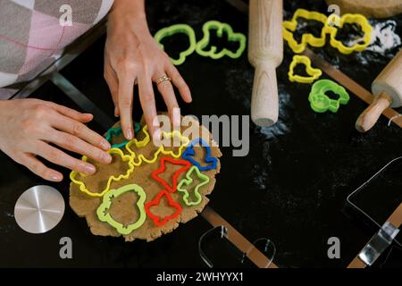 Confectioner distributes multi-colored cookie cutters over the dough on the table. Cropped Stock Photo