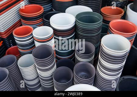 Many plastic pots of different shapes and colors for growing plants on the counter in a garden store Stock Photo