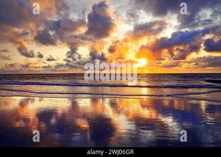 Sky with colorful clouds is reflected in the mudflat landscape at sunset, Norderney, Germany, Europe Stock Photo