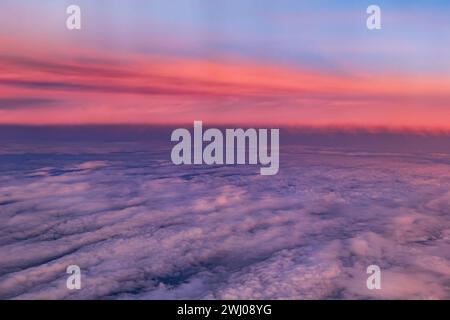 Aerial view background above the clouds with sunlit sky at sunset. Stock Photo
