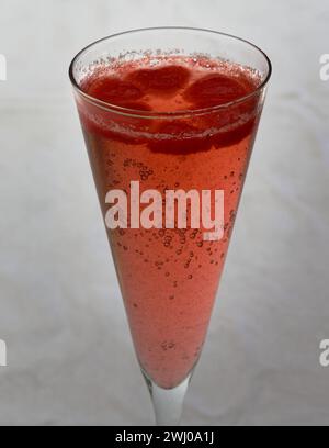 Pink ice cubes float on the service of a glass of bubbles in a champagne flute, Stock Photo