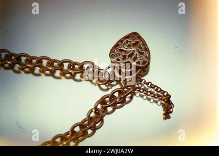 Large heart-shaped lock resting on a delicate chain bracelet Stock Photo
