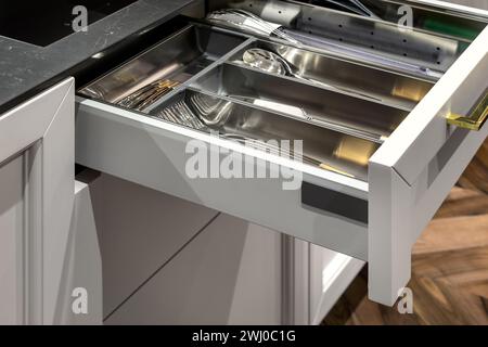 Metal kitchen drawer organizer in wood kitchen with simple set of kitchen tools, furniture details. Stock Photo