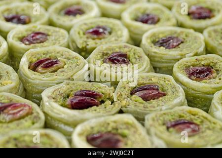 Traditional Turkish dessert, baklava, filled with crushed pistachios, decorated with whole nuts, abstract food background Stock Photo