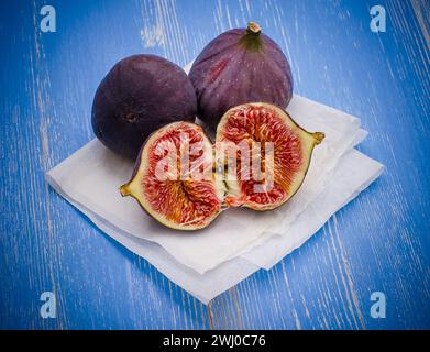 Three ripe figs on baking paper blue Stock Photo