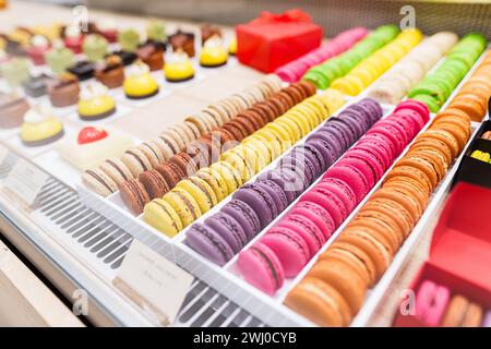 Close-up view of colorful macarons and other sweets on counter display in a bakery. High quality photo Stock Photo