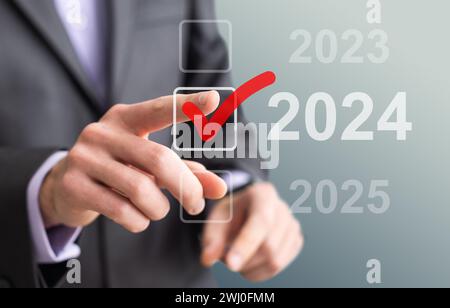 man hand touching on 2024 calender year button on digital virtual screen blur background Stock Photo