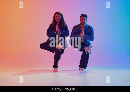 Dance duo, talented man and woman in dance poses against gradient studio background in neon light, filter. Stock Photo