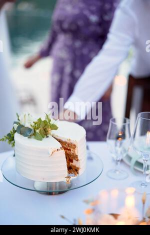 Wedding cake with a cut out piece stands on a stand on a festive table Stock Photo