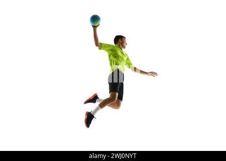 Dynamic image of young man in uniform, handball player in motion during game, practicing, jumping with ball against white studio background Stock Photo