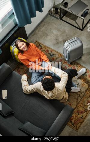 top view of a relaxed diverse couple sitting on the floor with a laptop, enjoying a cozy day indoors Stock Photo