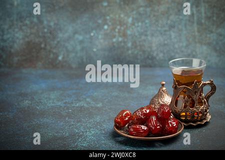 Breaking fasting with dried dates during Ramadan Kareem, Iftar meal with dates and Arab tea in traditional glass, angle view on Stock Photo