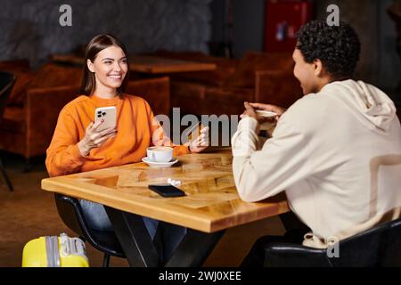 diverse couple sharing quiet conversation at table, woman holding smartphone and credit card Stock Photo